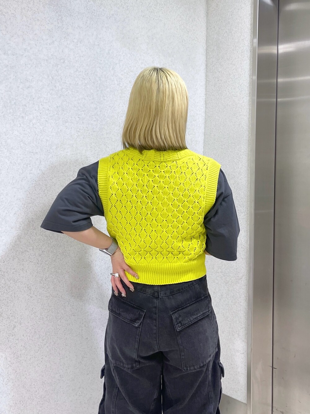 イエロー系のベスト、ホワイト系のショルダーバッグ、ブラック系のカーゴパンツを着用したレディースの春コーディネートの7枚目の写真