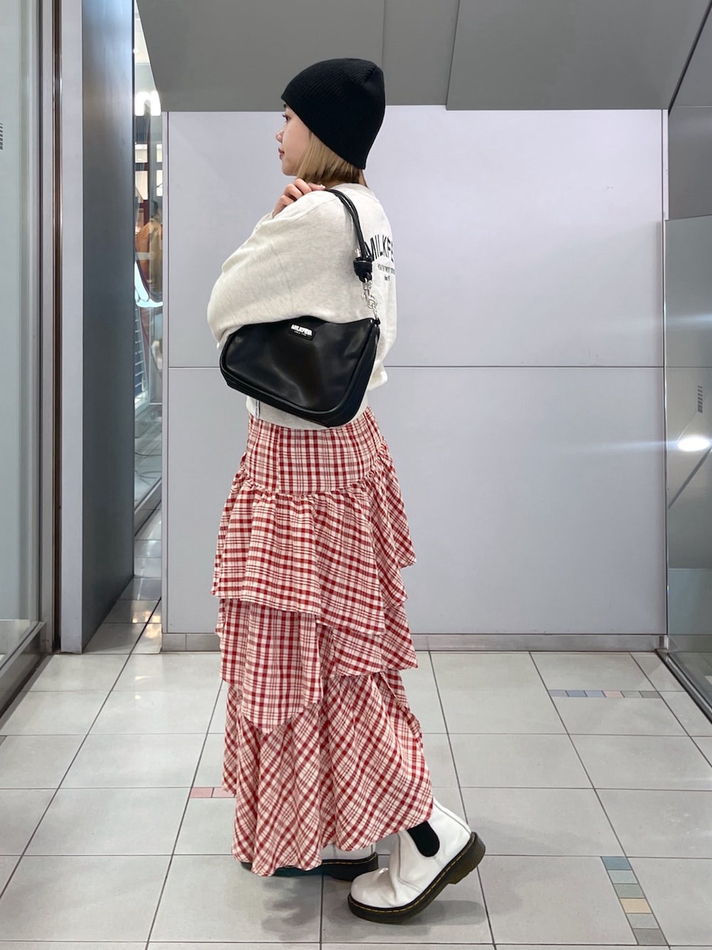 レッド系のスカート、ベージュ系のスウェット、ブラック系のショルダーバッグを着用したレディースの冬コーディネートの3枚目の写真