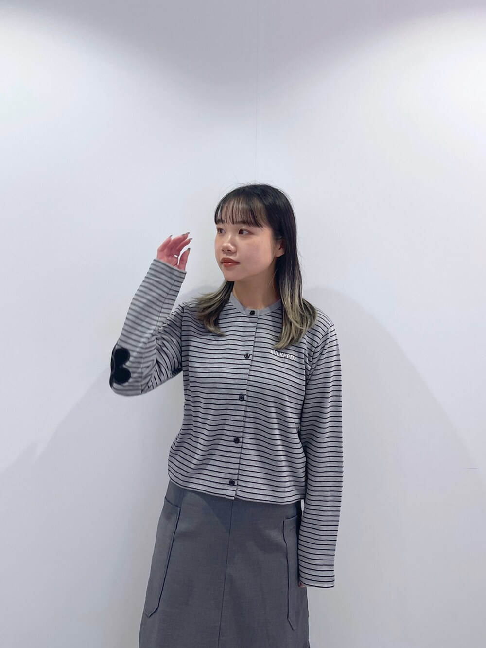 グレー系のスカート、ブラック系のショルダーバッグ、グレー系のカーディガン/ボレロを着用したレディースの秋コーディネートの6枚目の写真