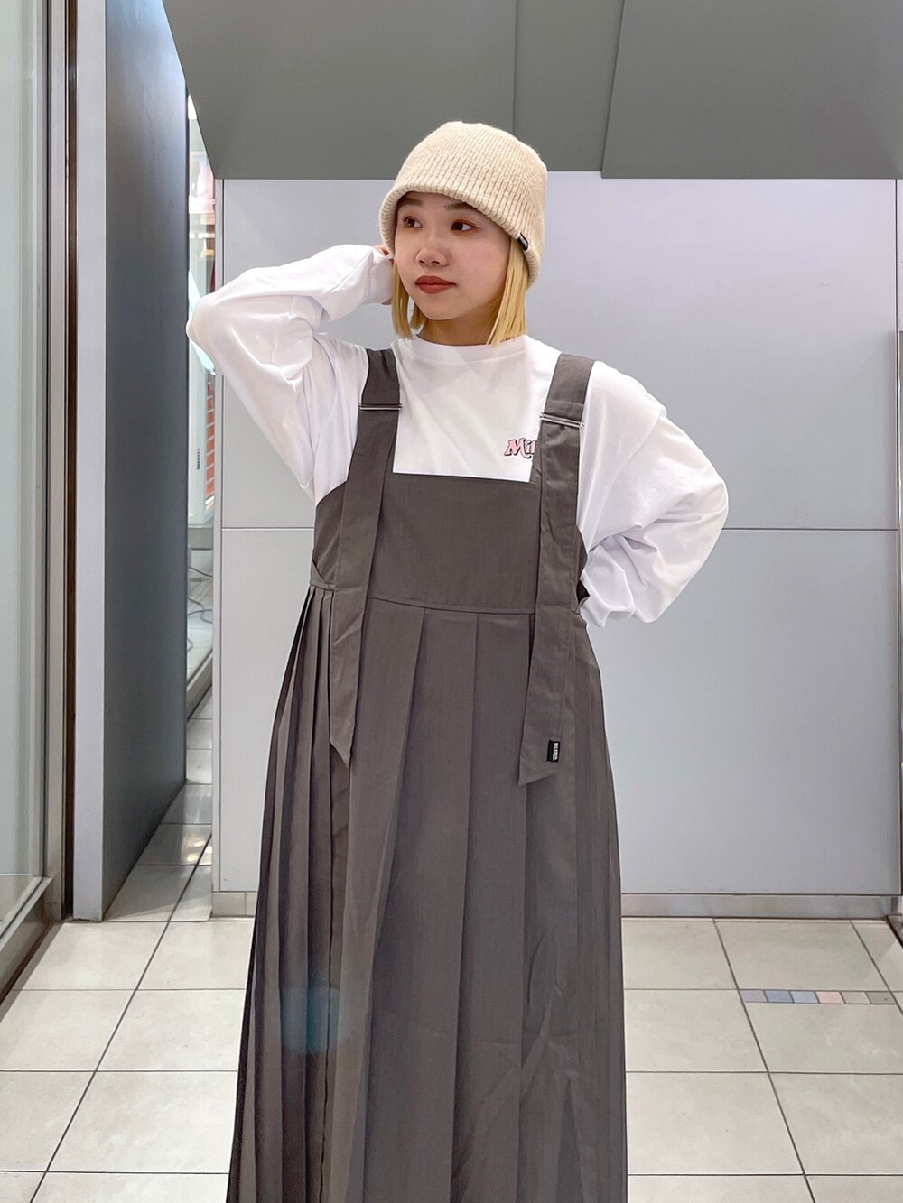 ホワイト系のTシャツ/カットソー、グレー系のジャンパースカート、ブラック系のショルダーバッグを着用したレディースの冬コーディネートの6枚目の写真