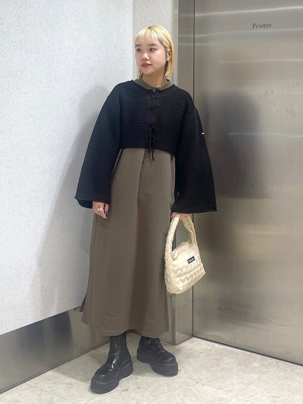 ブラック系のカーディガン/ボレロ、グリーン系のワンピース、ホワイト系のハンドバッグを着用したレディースの秋コーディネートの2枚目の写真