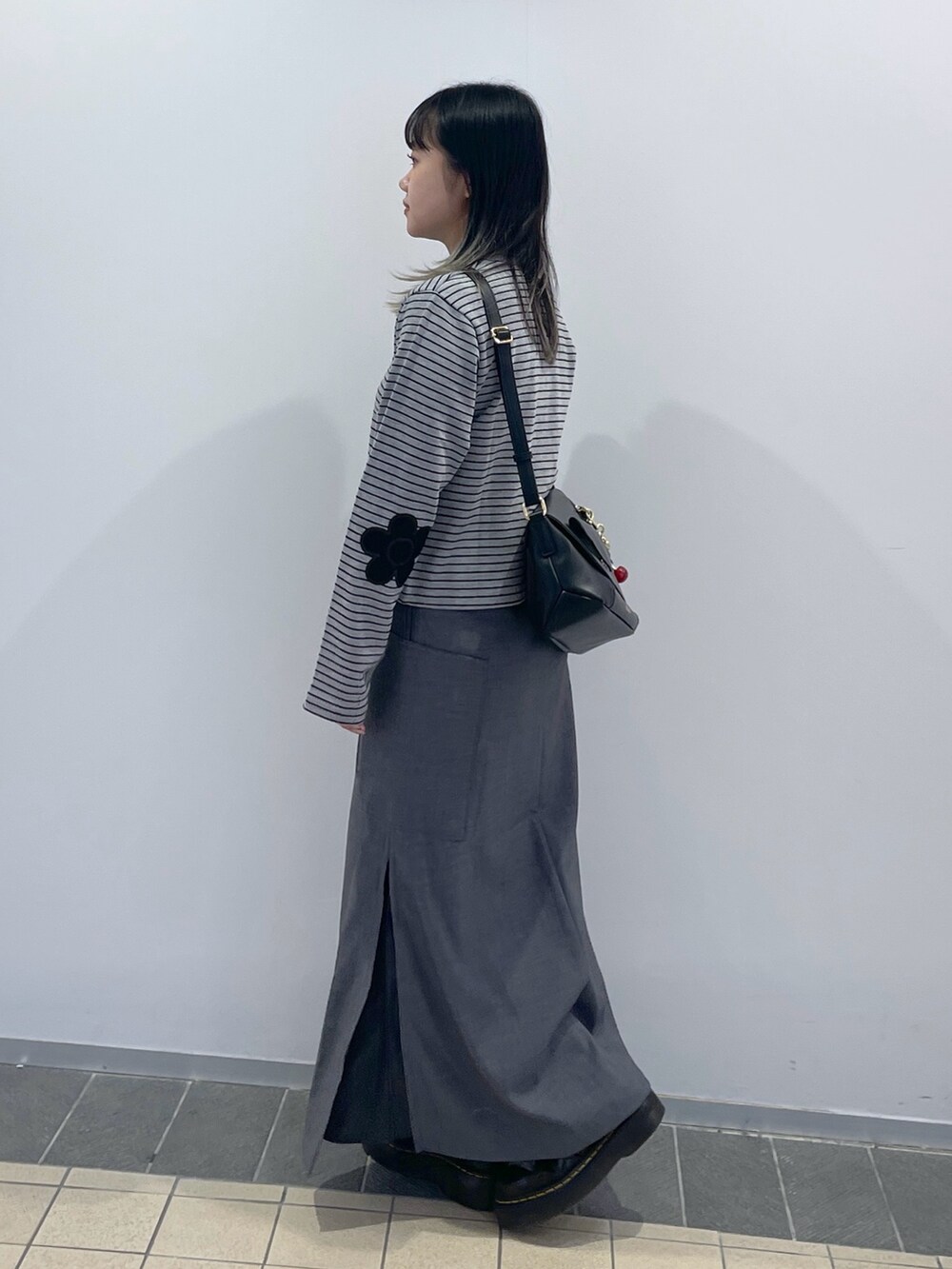 グレー系のスカート、ブラック系のショルダーバッグ、グレー系のカーディガン/ボレロを着用したレディースの秋コーディネートの4枚目の写真