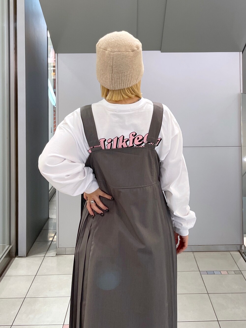 ホワイト系のTシャツ/カットソー、グレー系のジャンパースカート、ブラック系のショルダーバッグを着用したレディースの冬コーディネートの9枚目の写真