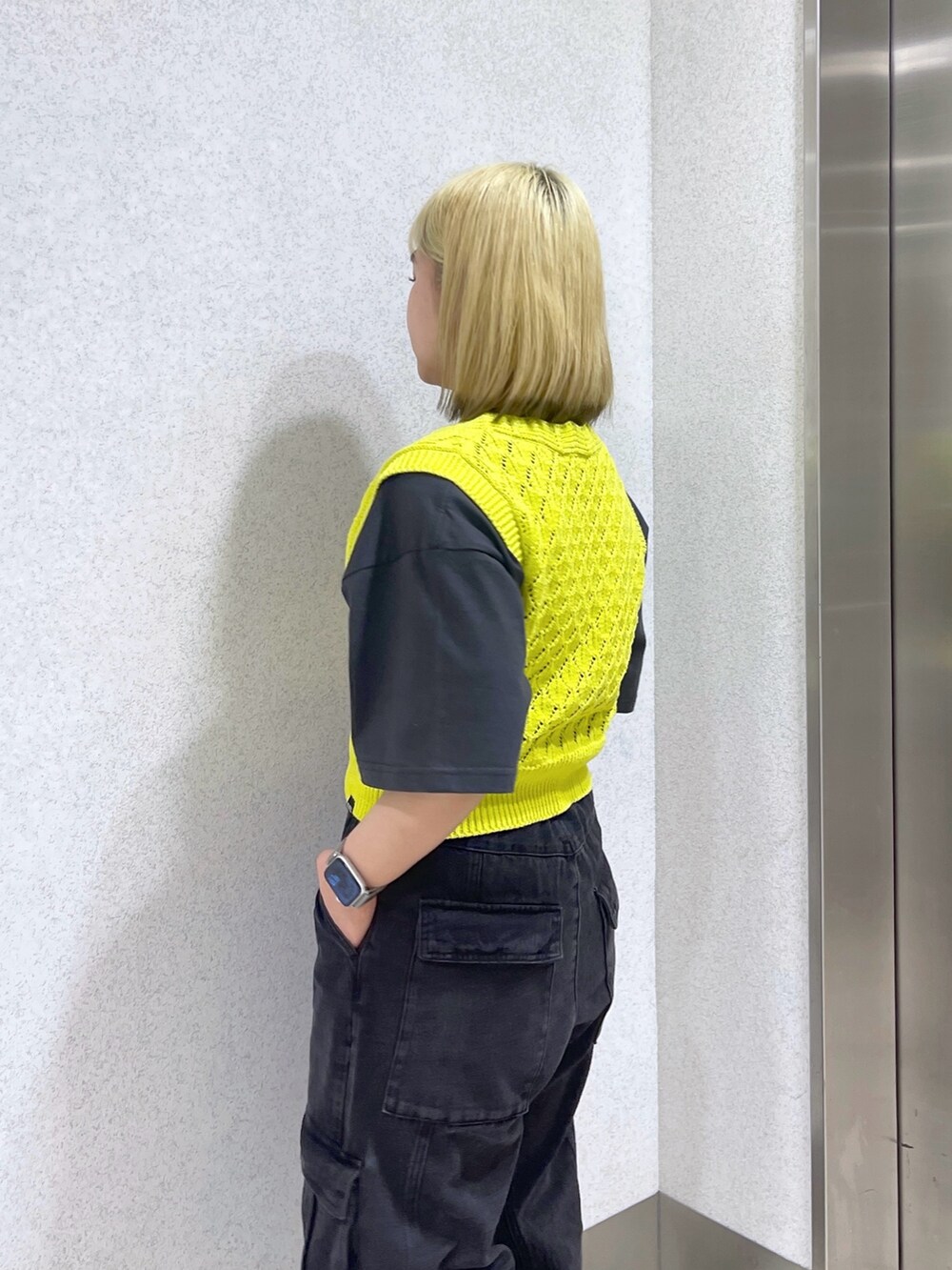 イエロー系のベスト、ホワイト系のショルダーバッグ、ブラック系のカーゴパンツを着用したレディースの春コーディネートの6枚目の写真