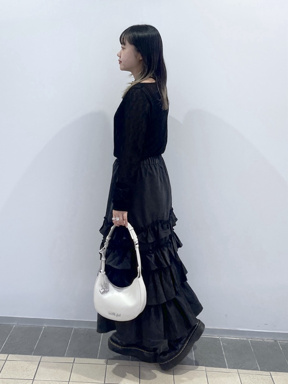 ブラック系のTシャツ/カットソー、ブラック系のスカート、ホワイト系のハンドバッグを着用したレディースの秋コーディネートの4枚目の写真