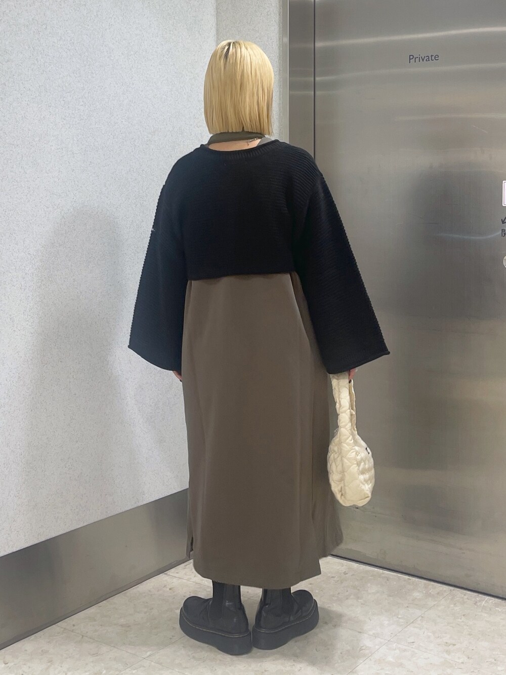 ブラック系のカーディガン/ボレロ、グリーン系のワンピース、ホワイト系のハンドバッグを着用したレディースの秋コーディネートの6枚目の写真