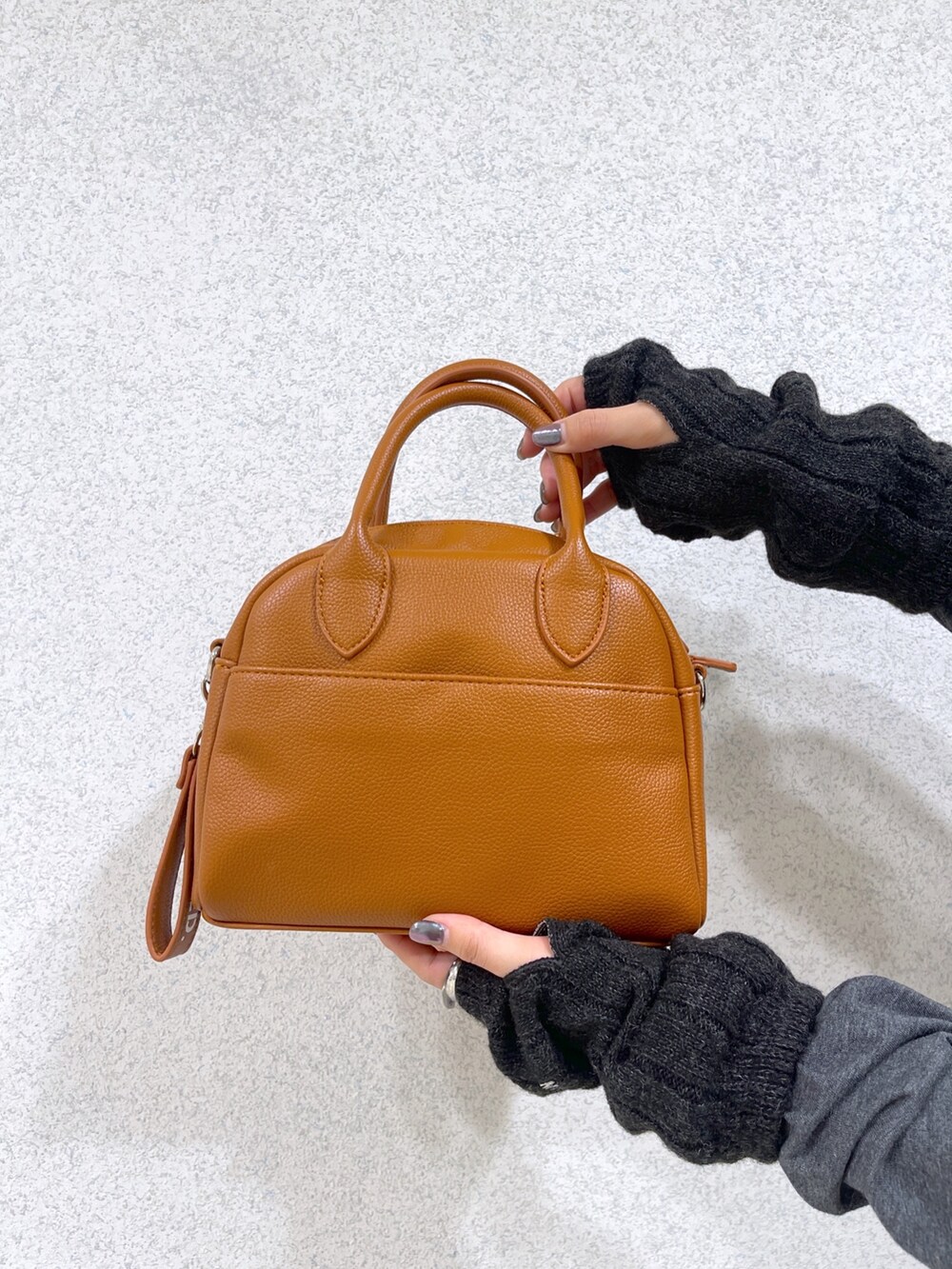 ブラック系のダウンベスト、ブラウン系のボストンバッグ、グレー系のワンピースを着用したレディースの秋コーディネートの10枚目の写真