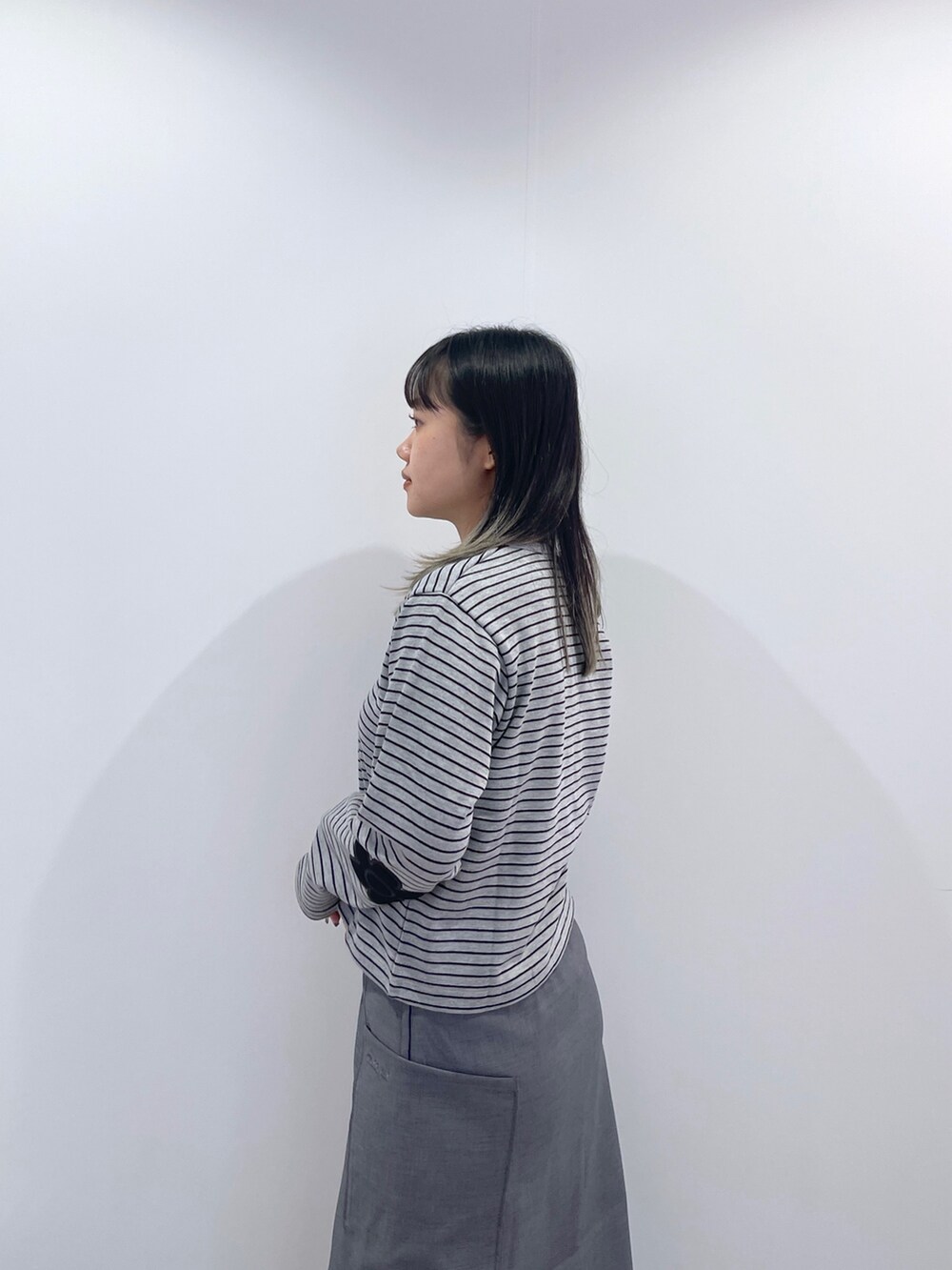 グレー系のスカート、ブラック系のショルダーバッグ、グレー系のカーディガン/ボレロを着用したレディースの秋コーディネートの7枚目の写真