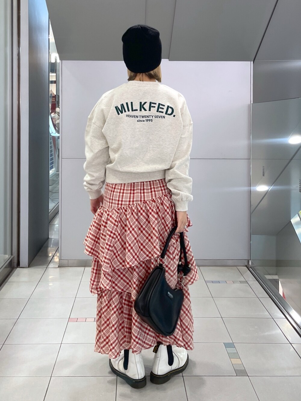 レッド系のスカート、ベージュ系のスウェット、ブラック系のショルダーバッグを着用したレディースの冬コーディネートの4枚目の写真