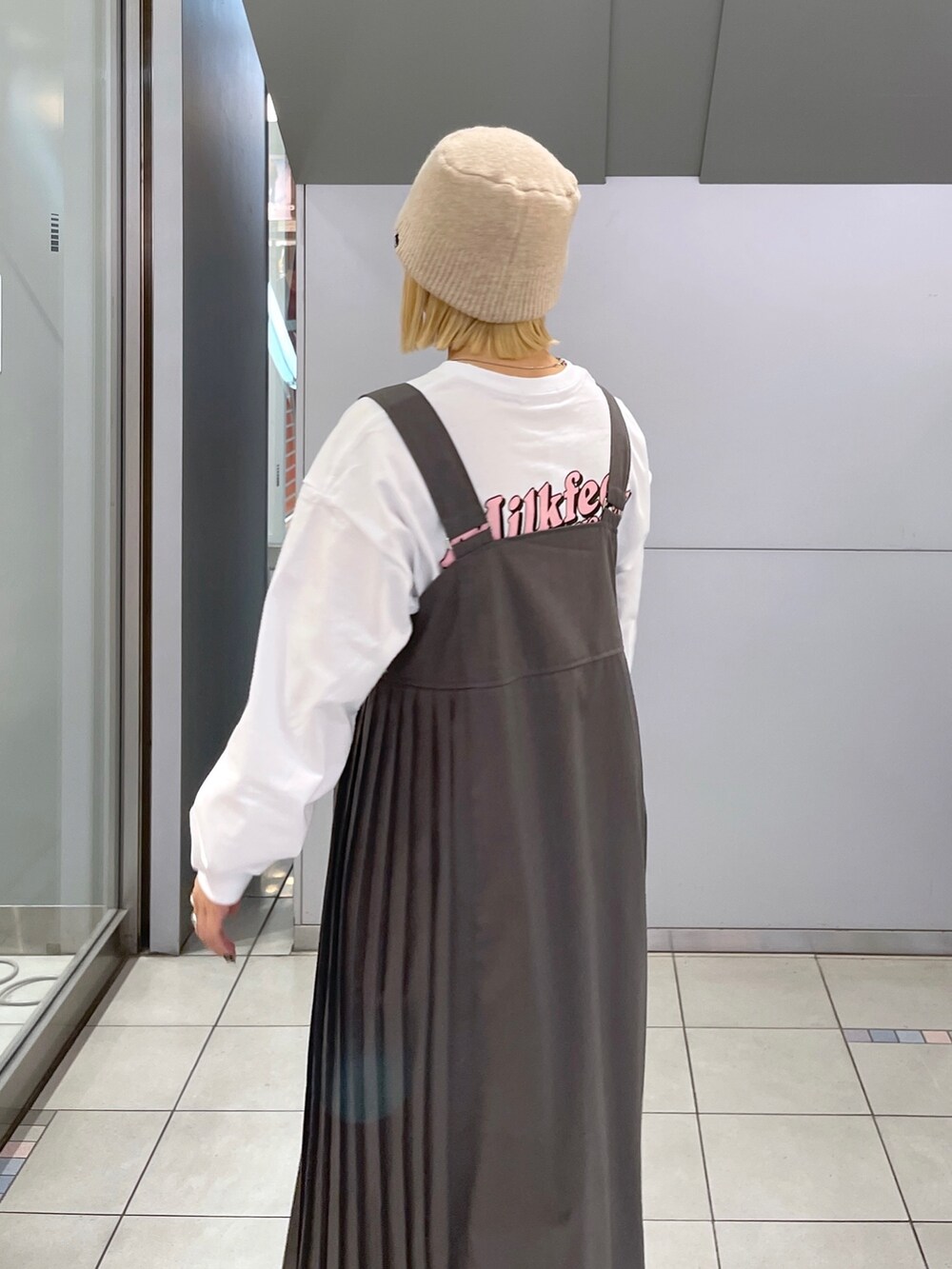 ホワイト系のTシャツ/カットソー、グレー系のジャンパースカート、ブラック系のショルダーバッグを着用したレディースの冬コーディネートの8枚目の写真