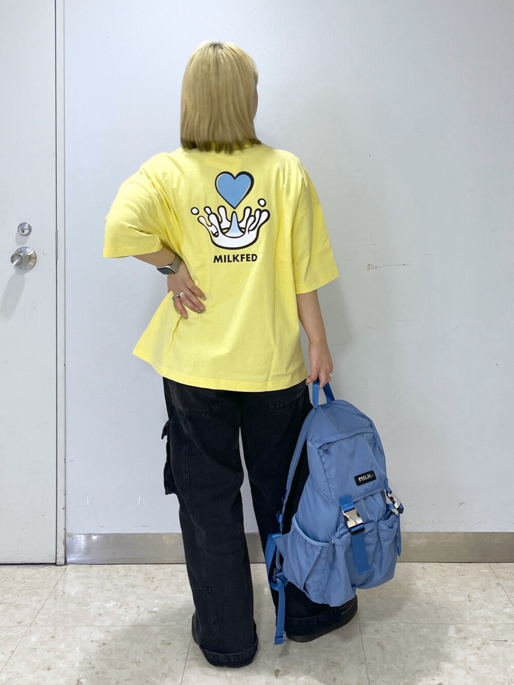 ブラック系のカーゴパンツ、ブルー系のバックパック/リュック、イエロー系のTシャツ/カットソーを着用したレディースの春コーディネートの2枚目の写真