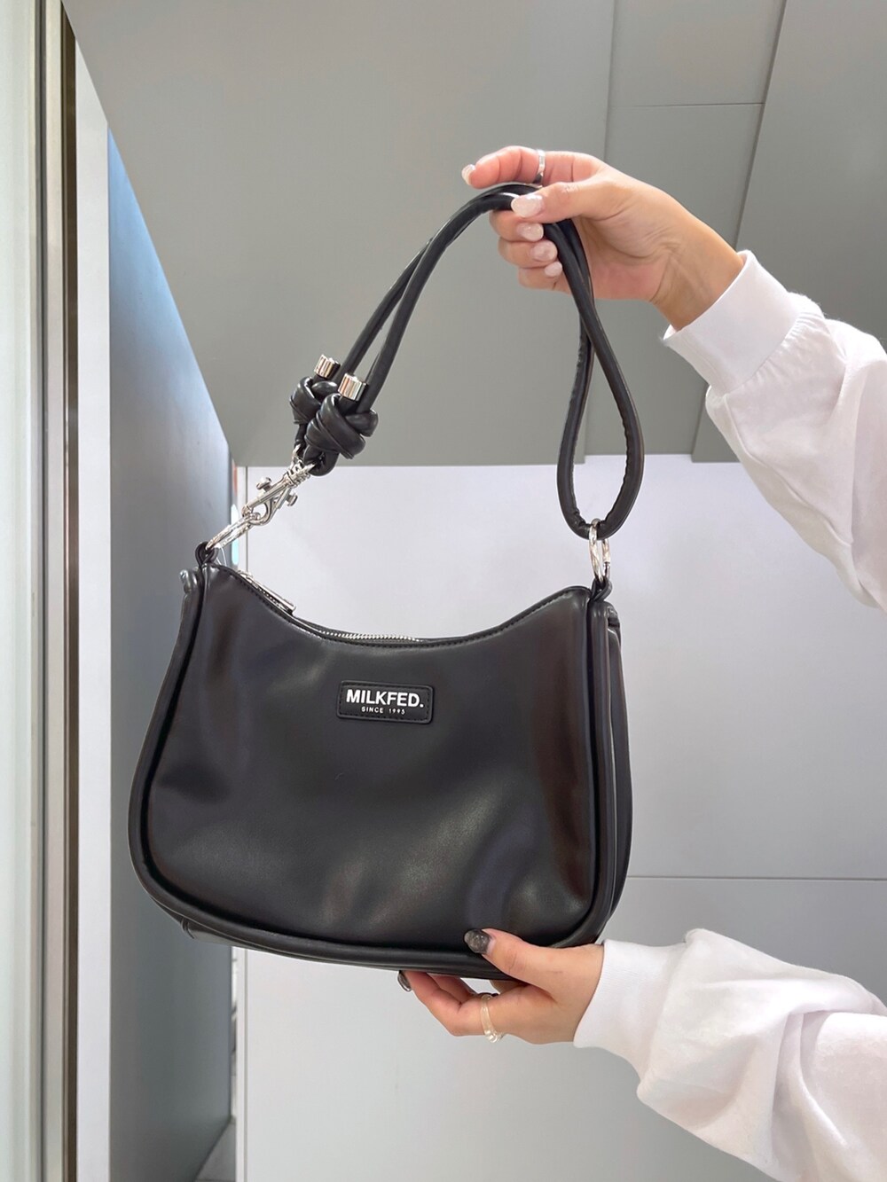 ホワイト系のTシャツ/カットソー、グレー系のジャンパースカート、ブラック系のショルダーバッグを着用したレディースの冬コーディネートの10枚目の写真