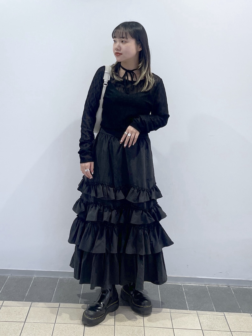 ブラック系のTシャツ/カットソー、ブラック系のスカート、ホワイト系のハンドバッグを着用したレディースの秋コーディネートの2枚目の写真