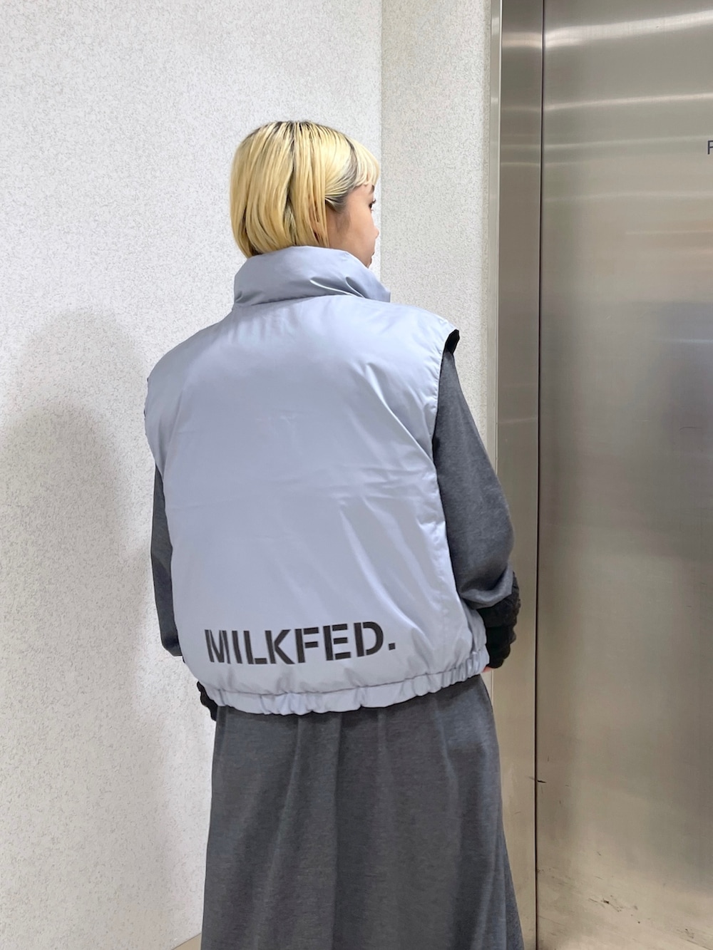 ブラック系のダウンベスト、ブラウン系のボストンバッグ、グレー系のワンピースを着用したレディースの秋コーディネートの7枚目の写真