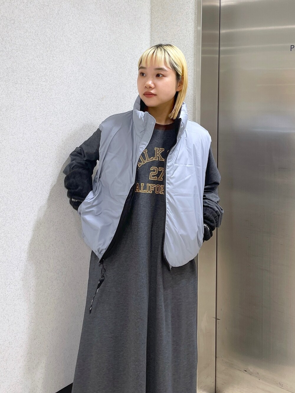 ブラック系のダウンベスト、ブラウン系のボストンバッグ、グレー系のワンピースを着用したレディースの秋コーディネートの6枚目の写真