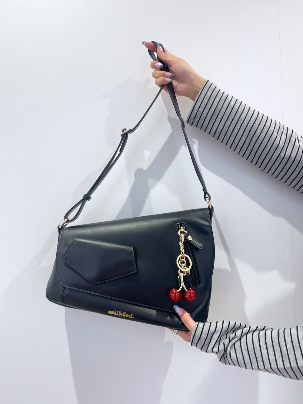 グレー系のスカート、ブラック系のショルダーバッグ、グレー系のカーディガン/ボレロを着用したレディースの秋コーディネートの9枚目の写真