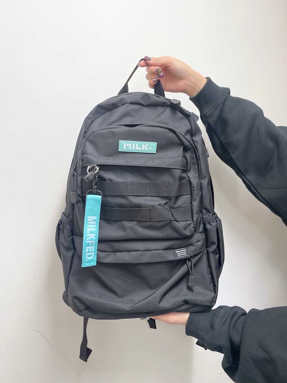 ブルー系のデニムパンツ、グリーン系のバックパック/リュック、ブラック系のスウェットを着用したレディースの秋コーディネートの9枚目の写真