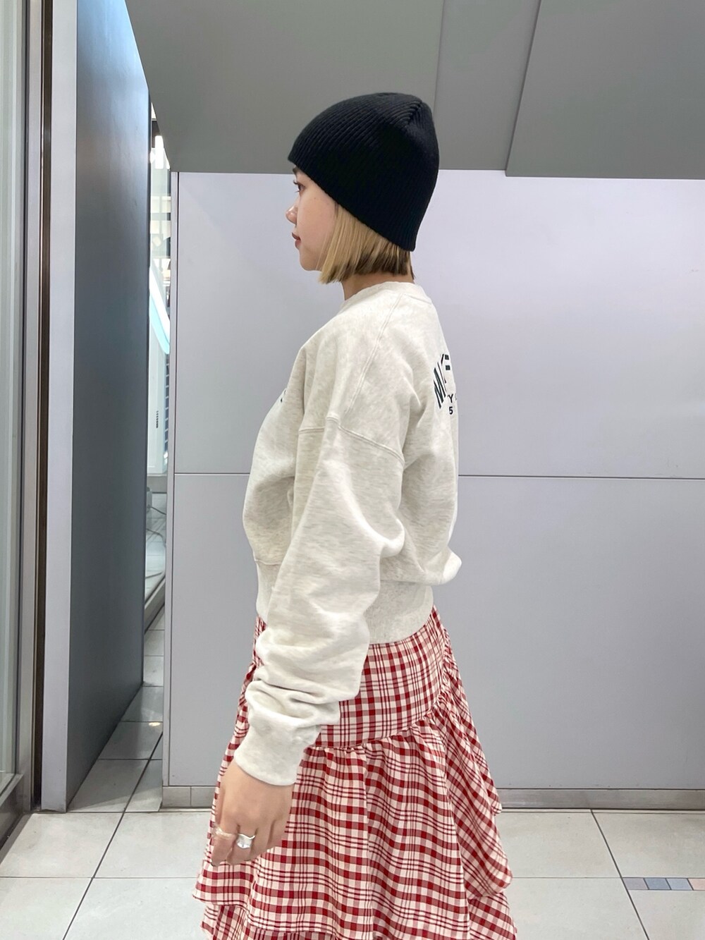 レッド系のスカート、ベージュ系のスウェット、ブラック系のショルダーバッグを着用したレディースの冬コーディネートの8枚目の写真