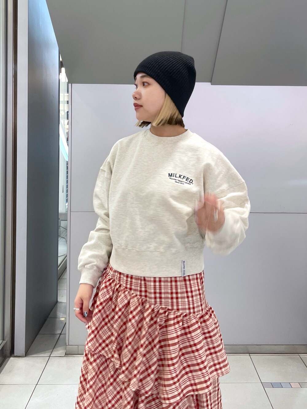 レッド系のスカート、ベージュ系のスウェット、ブラック系のショルダーバッグを着用したレディースの冬コーディネートの7枚目の写真