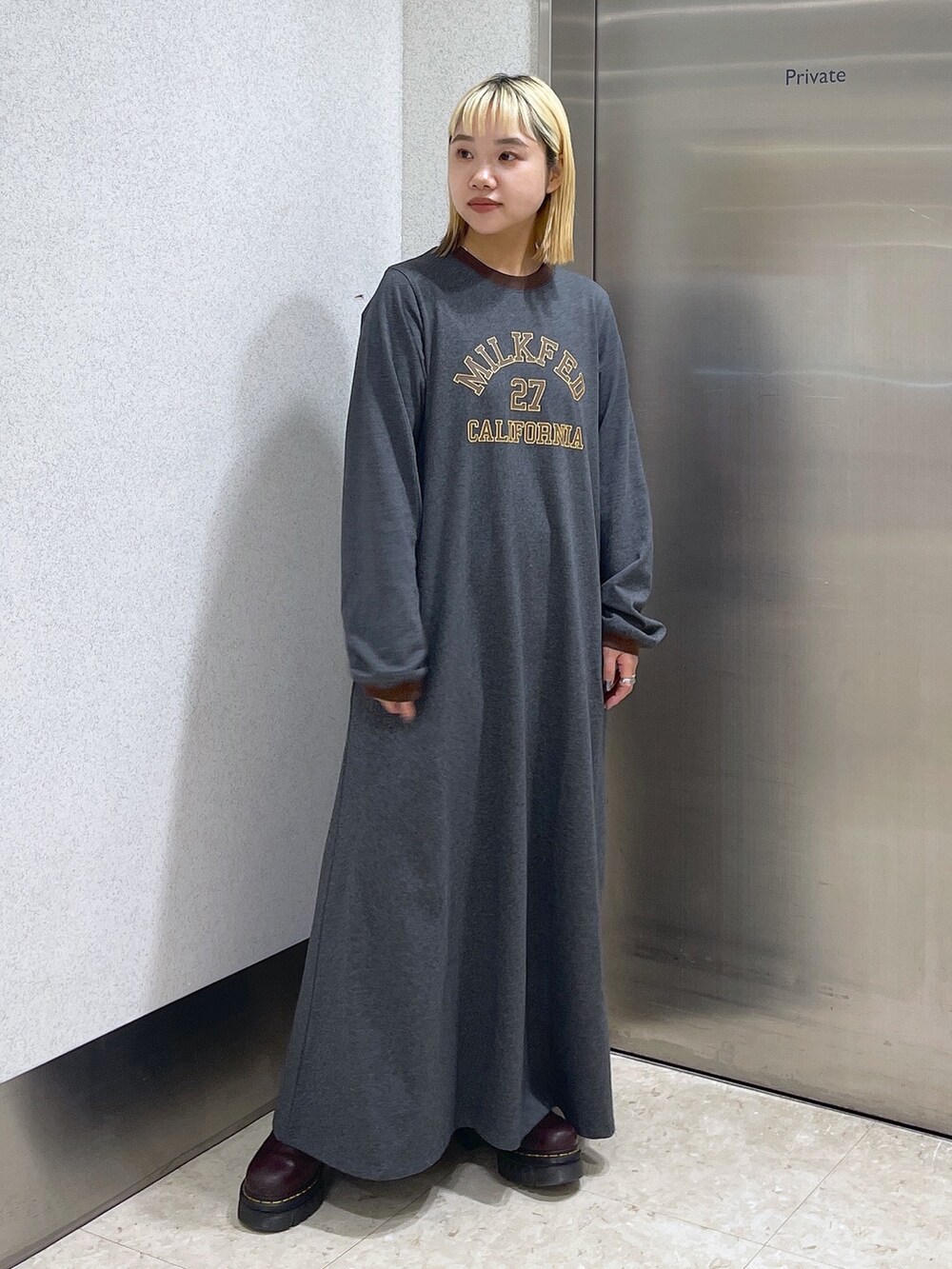 ブラック系のダウンベスト、ブラウン系のボストンバッグ、グレー系のワンピースを着用したレディースの秋コーディネートの8枚目の写真