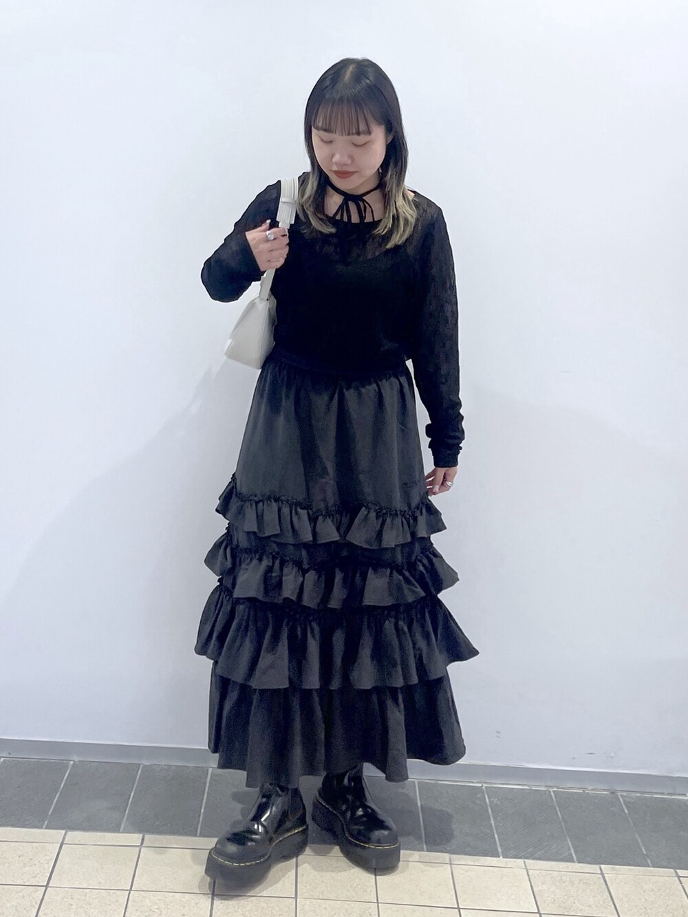 ブラック系のTシャツ/カットソー、ブラック系のスカート、ホワイト系のハンドバッグを着用したレディースの秋コーディネートの3枚目の写真