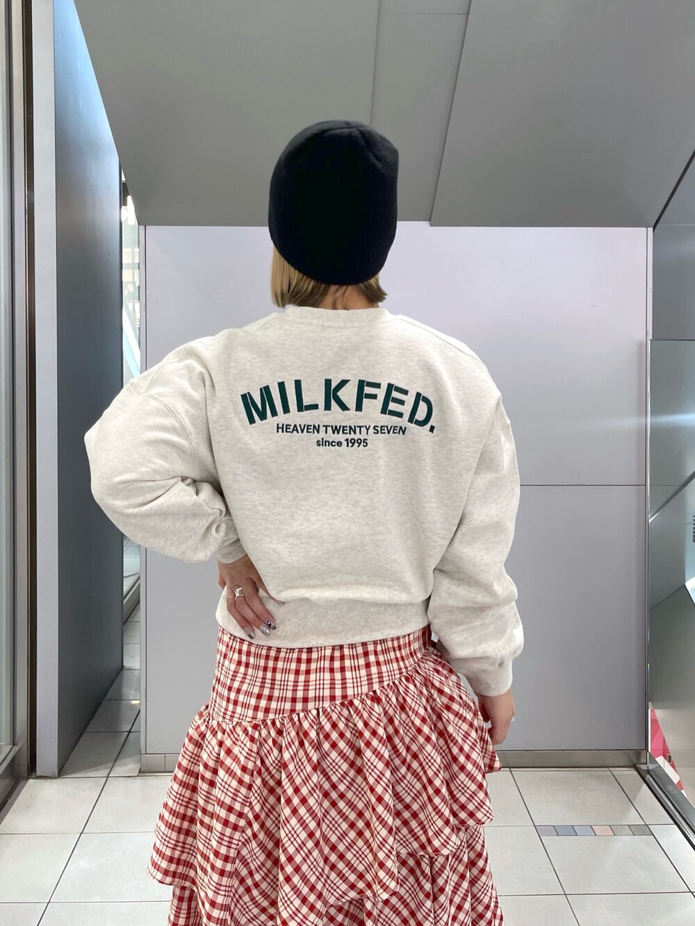 レッド系のスカート、ベージュ系のスウェット、ブラック系のショルダーバッグを着用したレディースの冬コーディネートの9枚目の写真