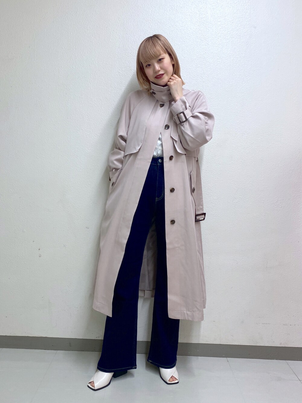 ベージュ系のトレンチコート、ブルー系のデニムパンツを着用したレディースの冬コーディネートの2枚目の写真