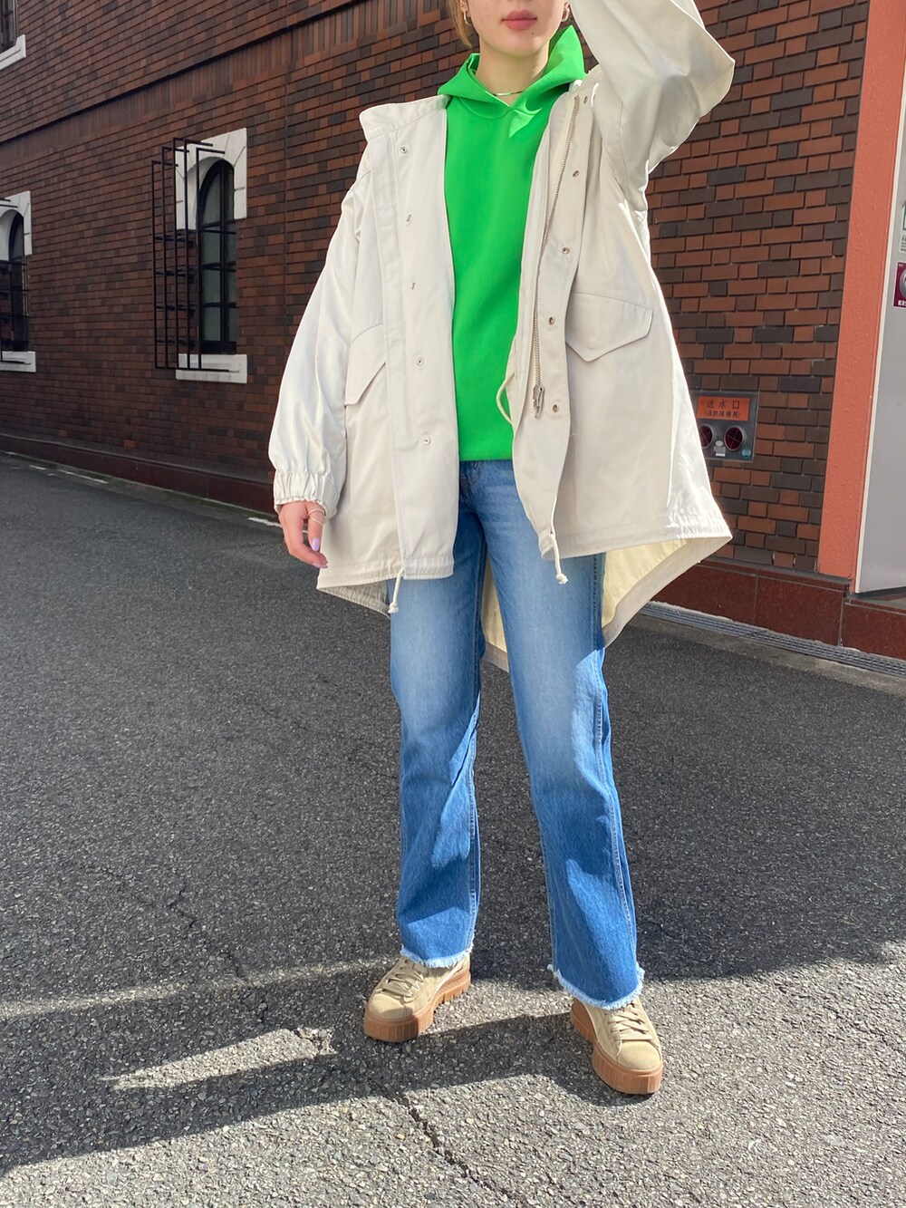 ホワイト系のモッズコート、グリーン系のパーカー、ブルー系のデニムパンツを着用したレディースの春コーディネートの3枚目の写真