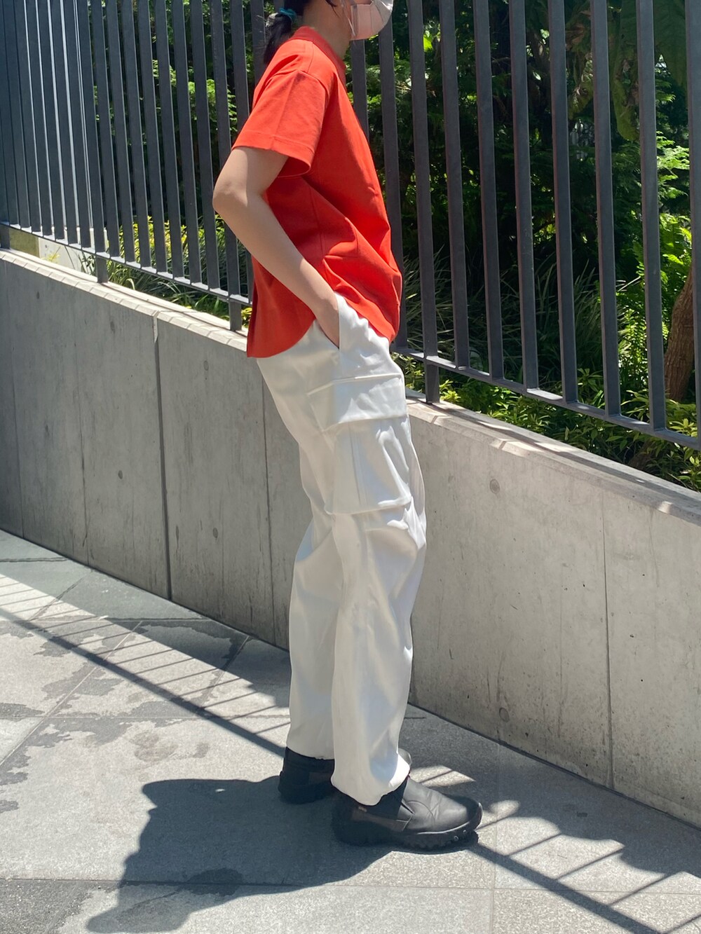 オレンジ系のTシャツ/カットソー、ホワイト系のカーゴパンツを着用したレディースの春コーディネートの3枚目の写真