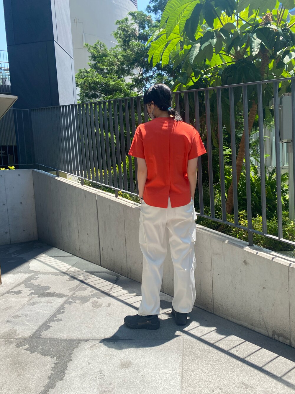 オレンジ系のTシャツ/カットソー、ホワイト系のカーゴパンツを着用したレディースの春コーディネートの2枚目の写真