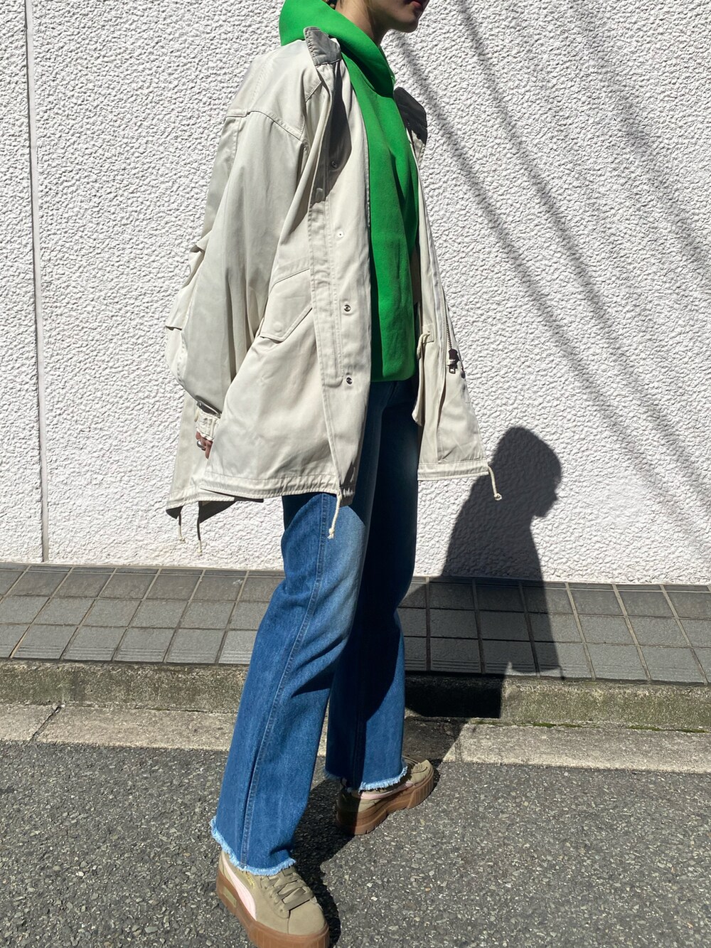 ベージュ系のモッズコート、グリーン系のパーカー、ブルー系のデニムパンツを着用したレディースの冬コーディネートの4枚目の写真