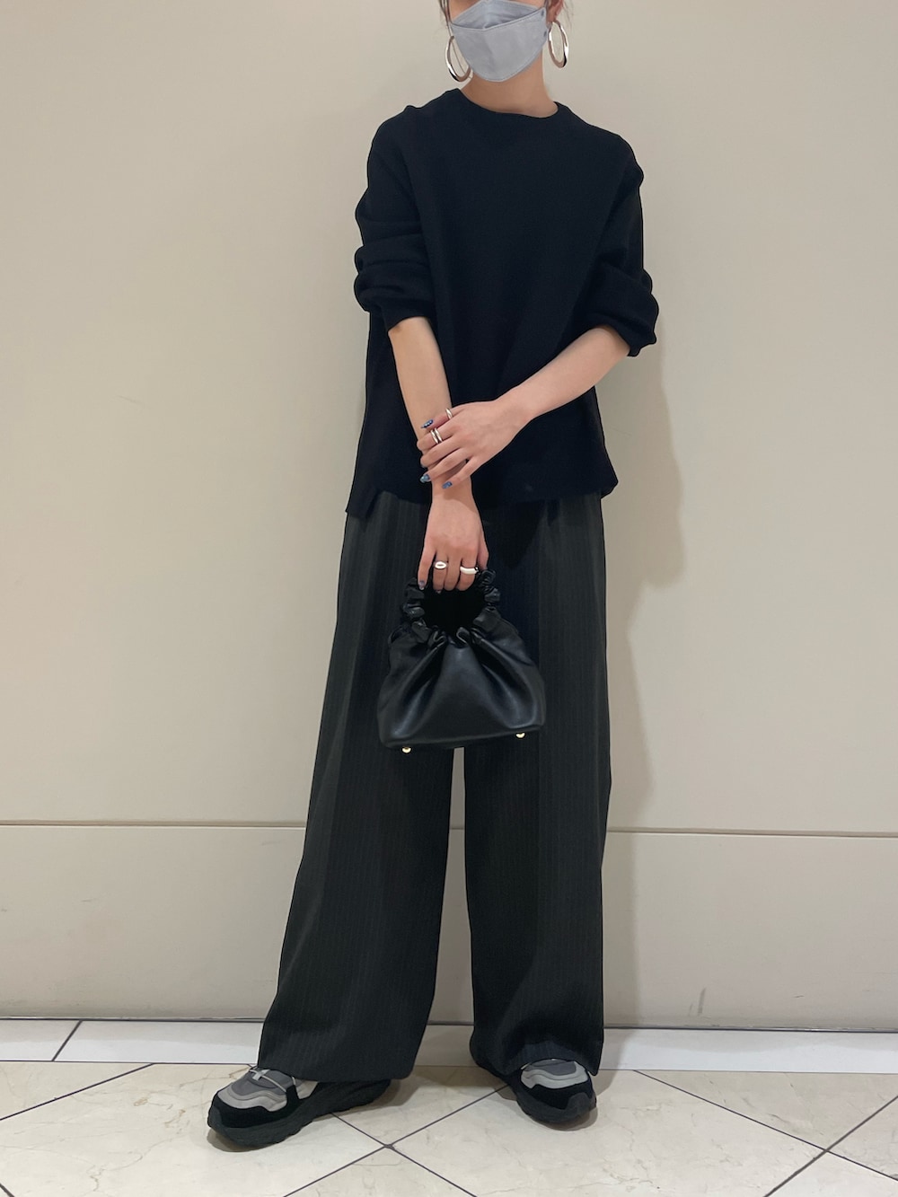 ブラック系のニット/セーター、グレー系のスラックス、ブラック系のハンドバッグを着用したレディースの秋コーディネートの4枚目の写真