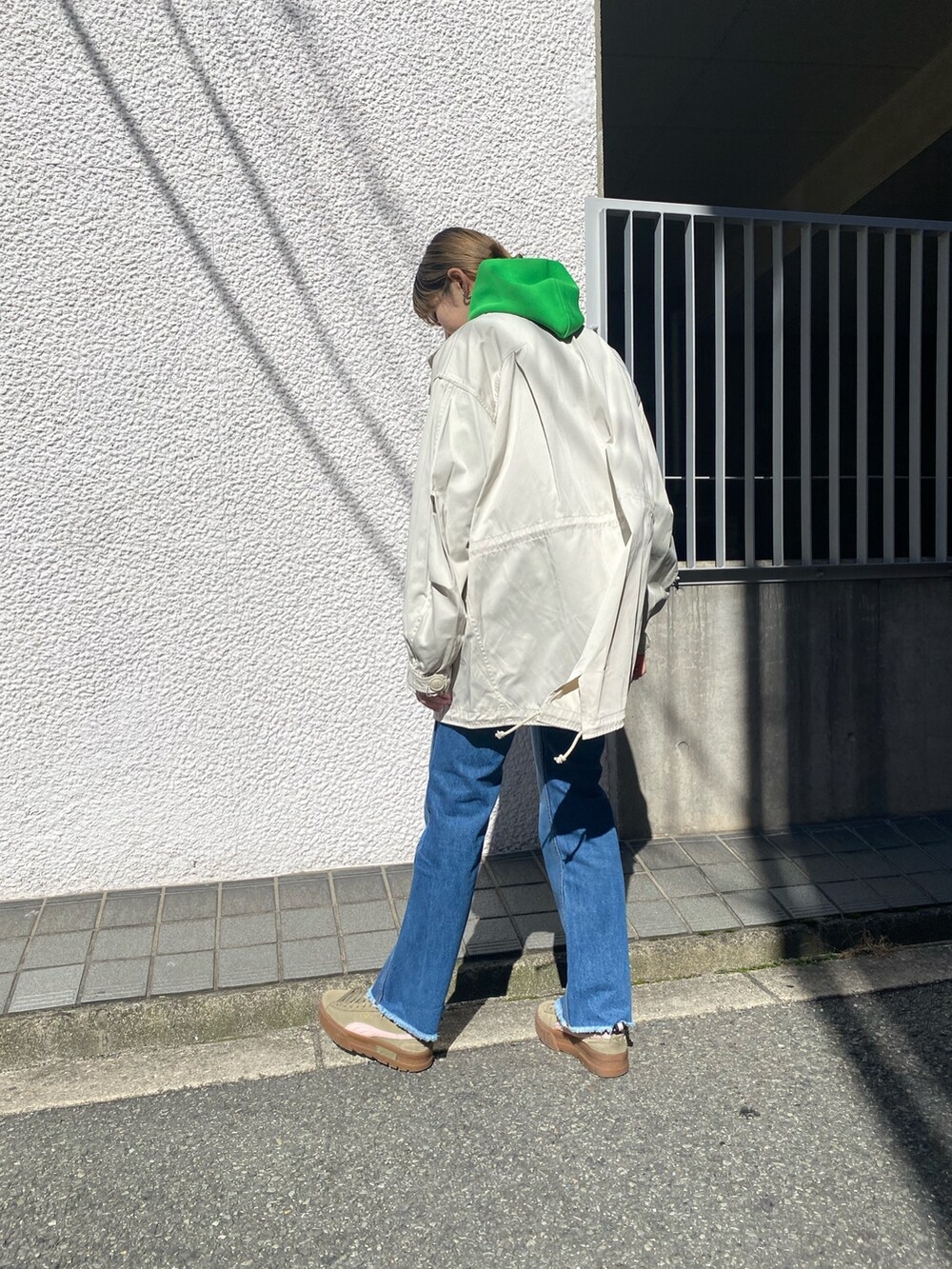 ベージュ系のモッズコート、グリーン系のパーカー、ブルー系のデニムパンツを着用したレディースの冬コーディネートの3枚目の写真