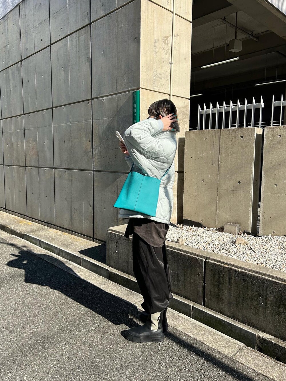 ブルー系のトートバッグ、ブラック系のブーツを着用したレディースの冬コーディネートの2枚目の写真