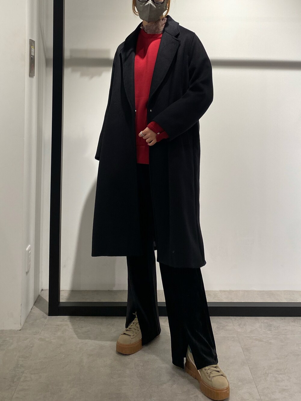 ブラック系のチェスターコート、レッド系のTシャツ/カットソーを着用したレディースの冬コーディネートの2枚目の写真