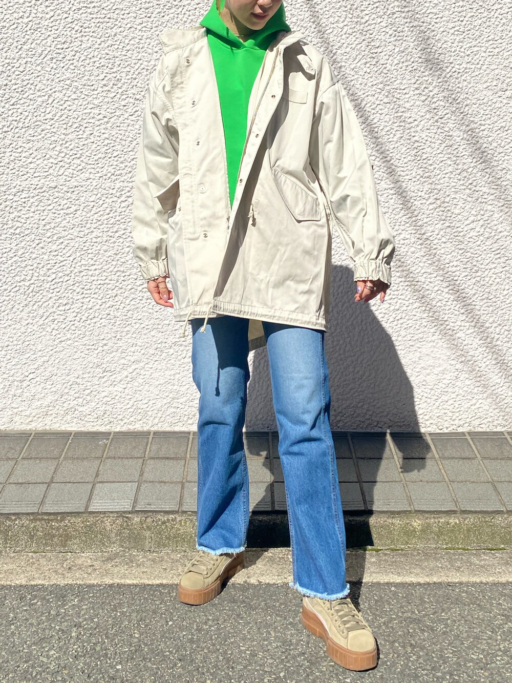 ベージュ系のモッズコート、グリーン系のパーカー、ブルー系のデニムパンツを着用したレディースの冬コーディネートの2枚目の写真