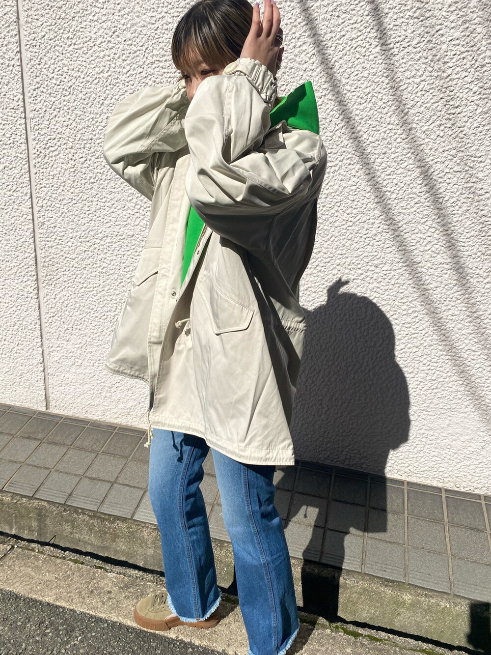 ホワイト系のモッズコート、グリーン系のパーカー、ブルー系のデニムパンツを着用したレディースの春コーディネートの2枚目の写真