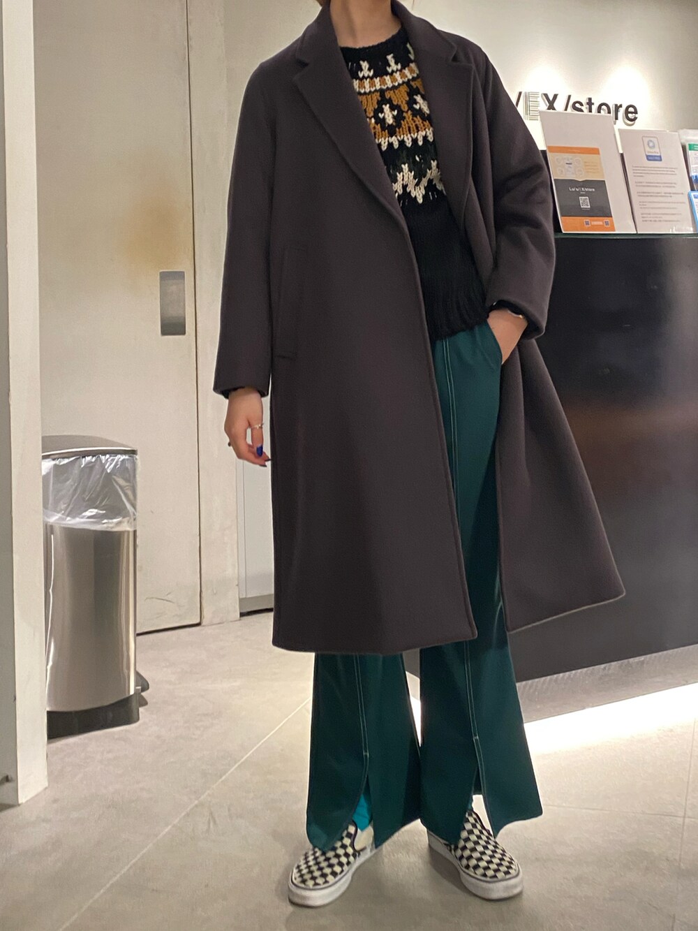 グレー系のチェスターコート、グリーン系のその他パンツ、ブラック系のニット/セーターを着用したレディースの冬コーディネートの2枚目の写真