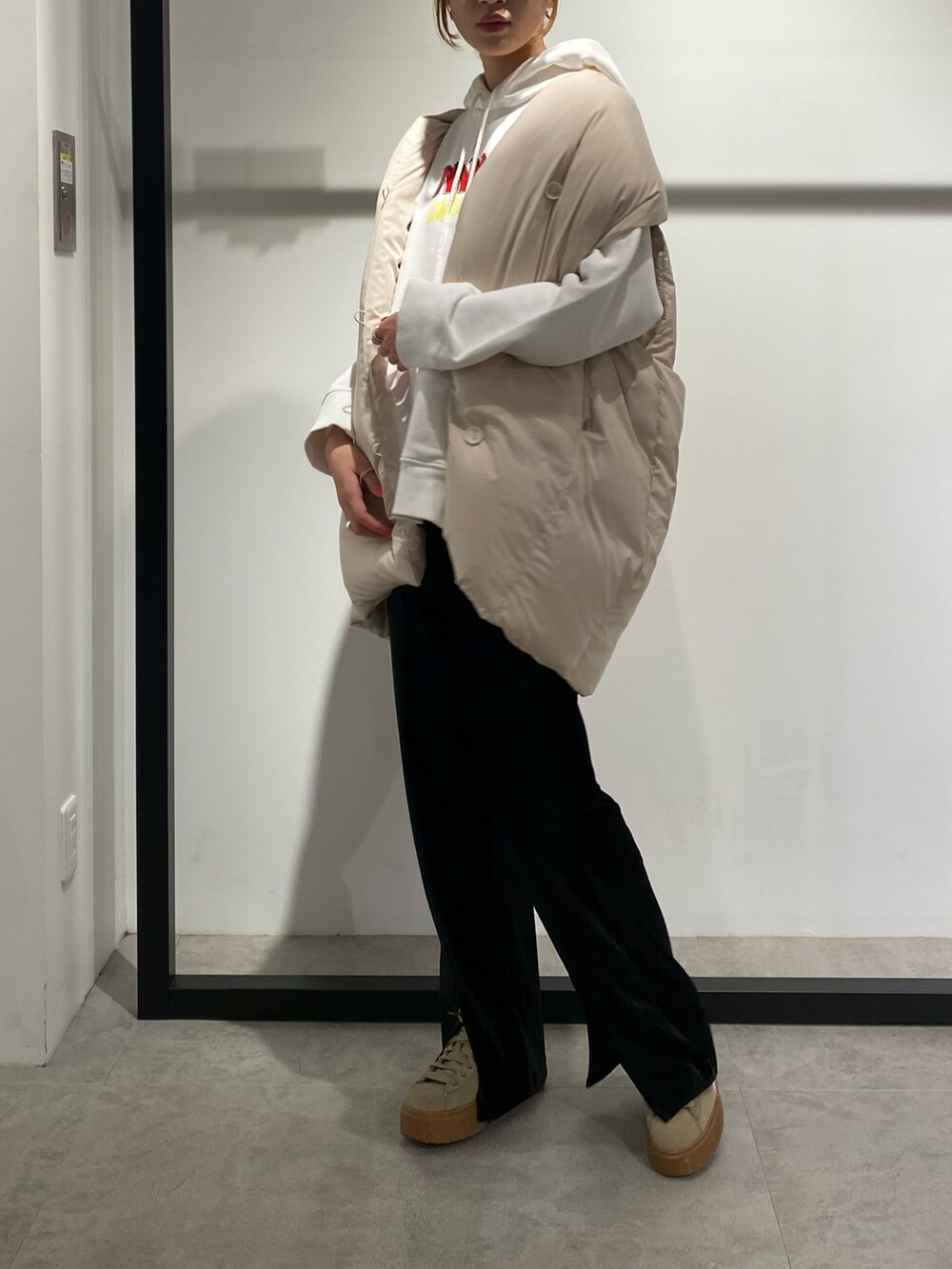 ホワイト系のダウンベスト、ブラック系のその他パンツを着用したレディースの冬コーディネートの2枚目の写真