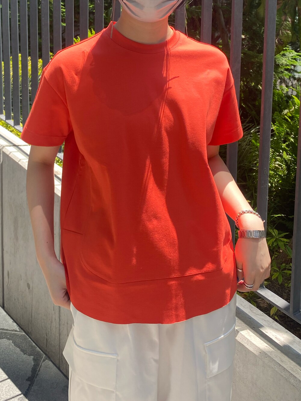 オレンジ系のTシャツ/カットソー、ホワイト系のカーゴパンツを着用したレディースの春コーディネートの4枚目の写真