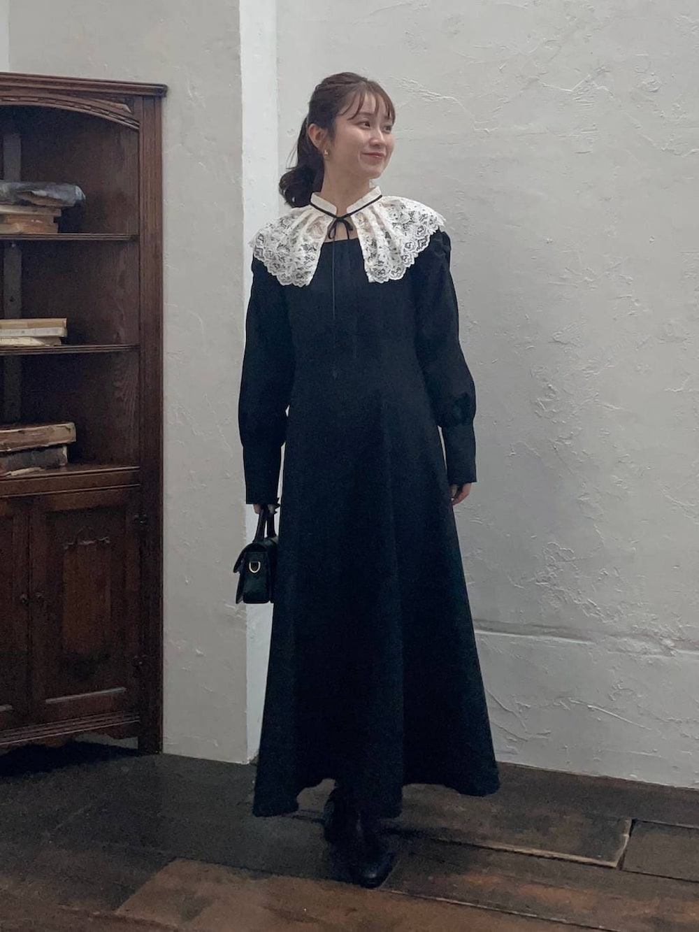 ホワイト系のチェスターコート、ブラック系のブーツ、ブラック系のショルダーバッグを着用したレディースの冬コーディネートの3枚目の写真