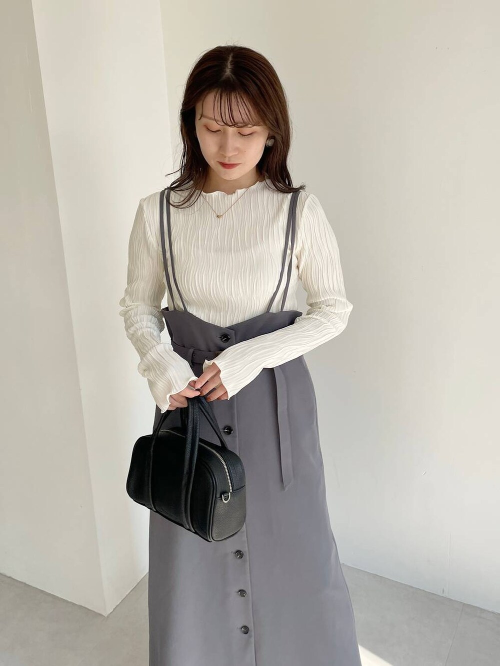 ブラック系のボストンバッグ、ブラック系のブーツ、グレー系のスカートを着用したレディースの秋コーディネートの8枚目の写真