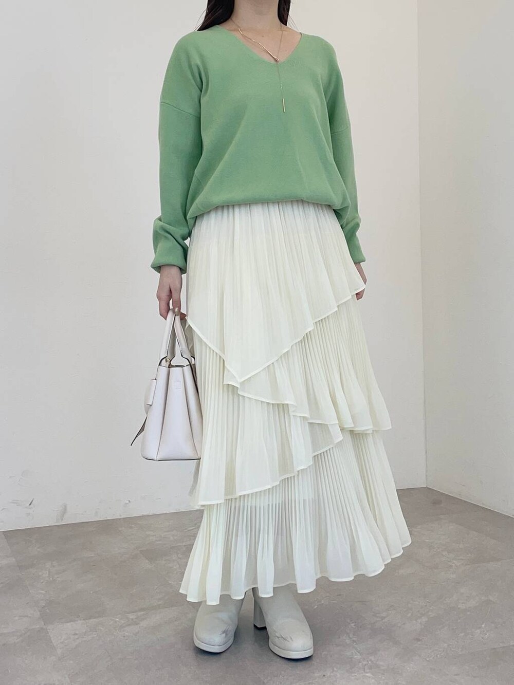 ホワイト系のブーツ、グリーン系のニット/セーター、ホワイト系のショルダーバッグを着用したレディースの冬コーディネートの4枚目の写真