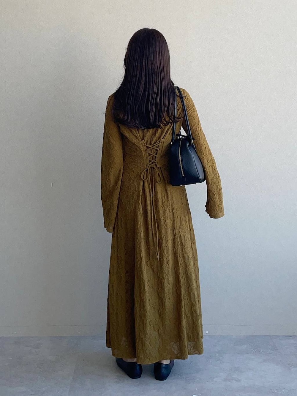 ブラック系のハンドバッグ、イエロー系のワンピース、ブラック系のバレエシューズを着用したレディースの秋コーディネートの2枚目の写真