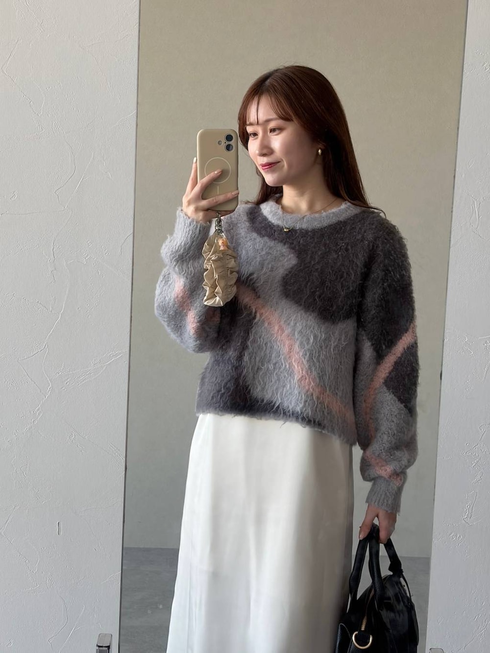 グレー系のニット/セーター、ブラック系のボストンバッグ、ブルー系のデニムパンツを着用したレディースの冬コーディネートの3枚目の写真