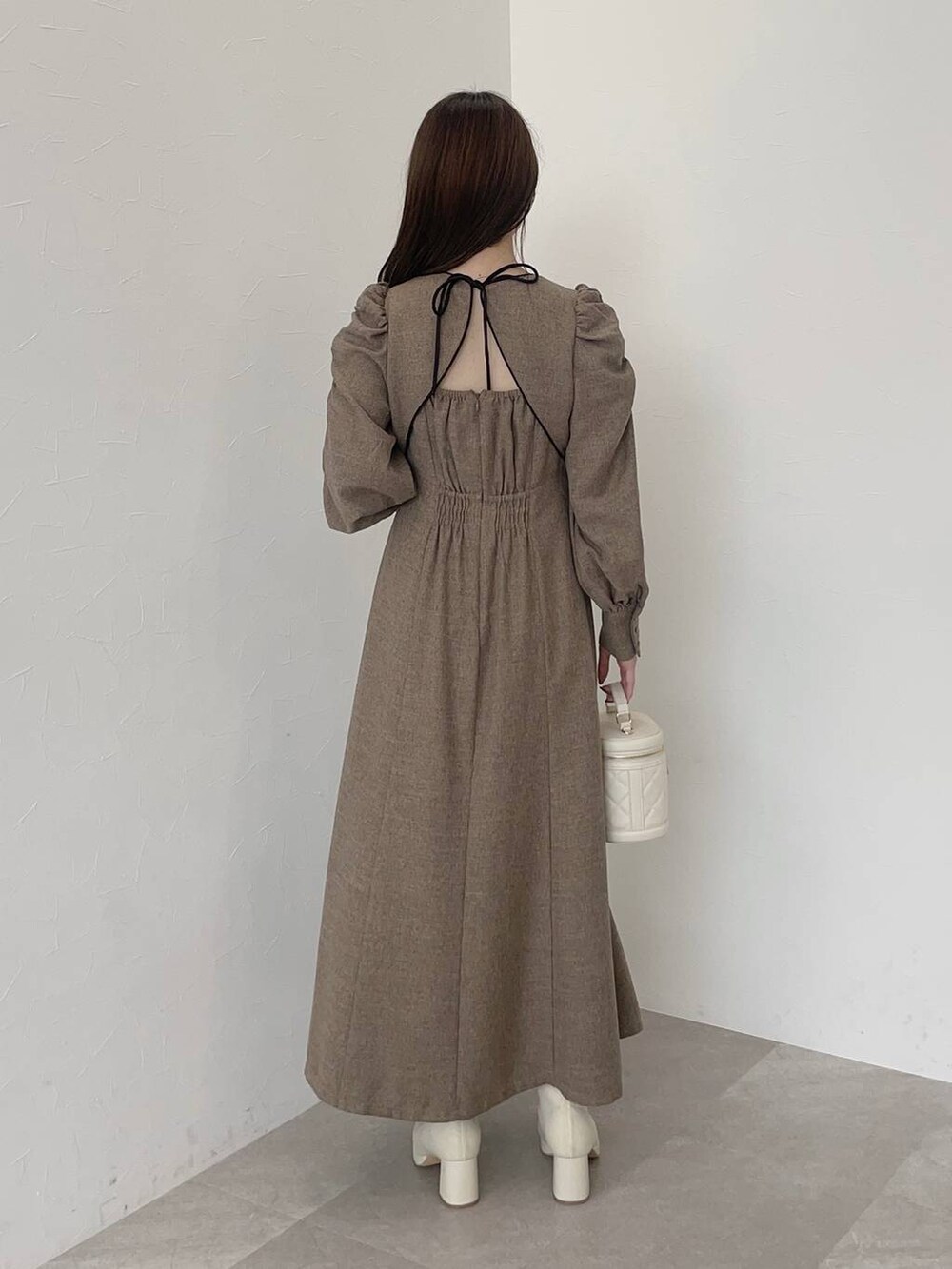 ブラック系のその他アウター、ホワイト系のブーツ、ホワイト系のショルダーバッグを着用したレディースの秋コーディネートの4枚目の写真