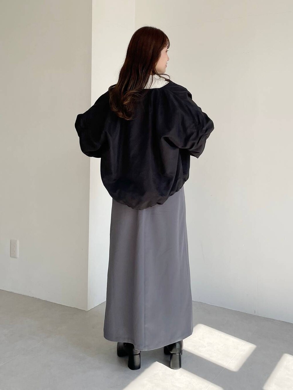 ブラック系のボストンバッグ、ブラック系のブーツ、グレー系のスカートを着用したレディースの秋コーディネートの2枚目の写真