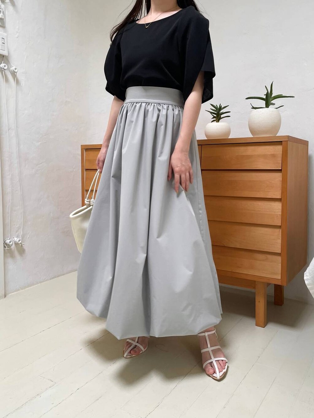 ホワイト系のハンドバッグ、ホワイト系のサンダル、グリーン系のスカートを着用したレディースの夏コーディネートの4枚目の写真