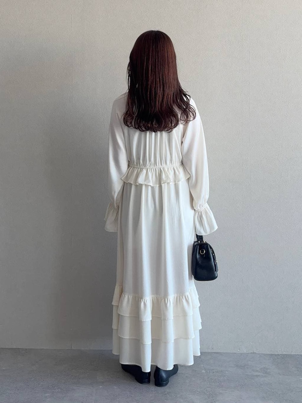 ブラック系のショルダーバッグ、ブラック系のパンプス、ホワイト系のワンピースを着用したレディースの冬コーディネートの5枚目の写真