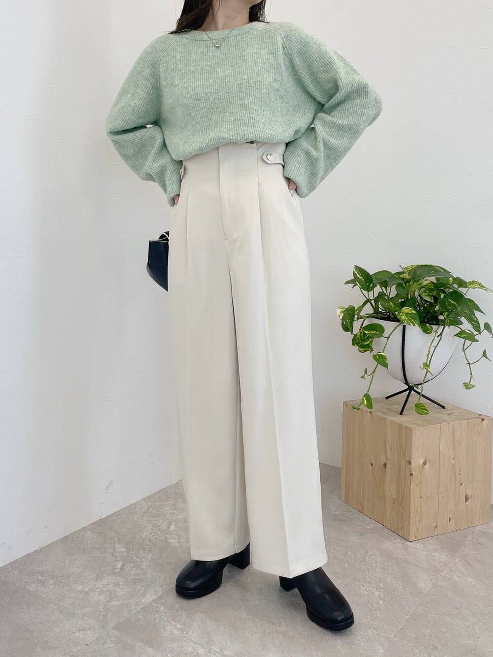 グリーン系のニット/セーター、ブラック系のハンドバッグ、ブラック系のブーツを着用したレディースの冬コーディネートの4枚目の写真